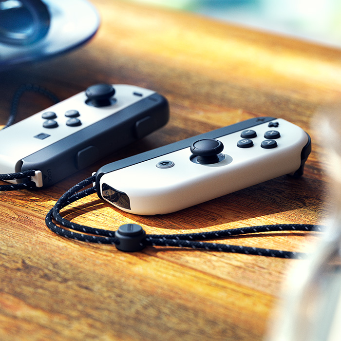 White Nintendo Switch Joy-Con controllers and wrist straps on a table