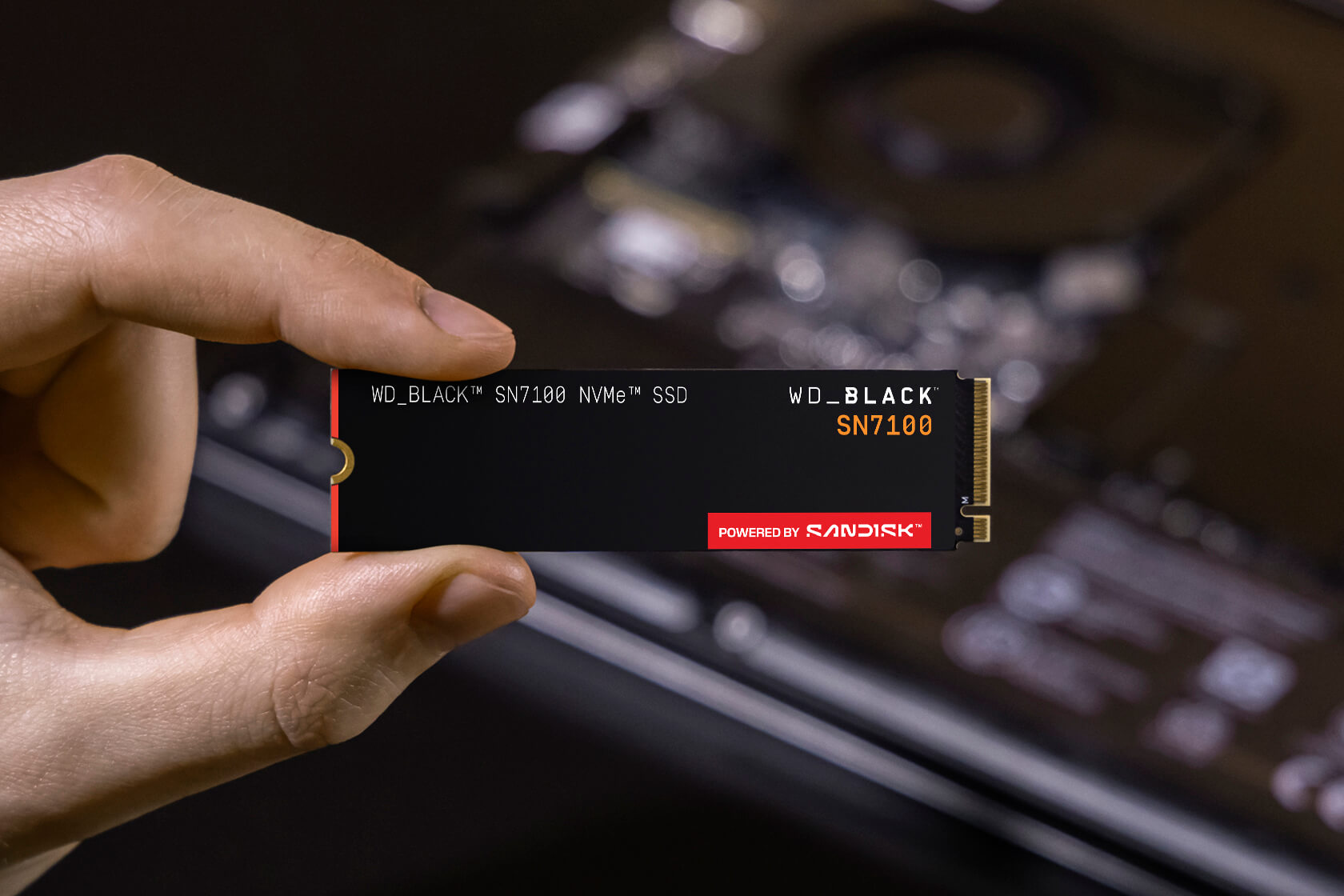 WD_BLACK SN7100 SSD held beside a laptop